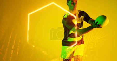 Téléchargez les photos : Joueur masculin caucasien attrapant la balle de rugby par hexagone illuminé et plantes sur fond jaune. Copier l'espace, composite, sport, compétition, forme, nature, jeu, match et concept abstrait. - en image libre de droit