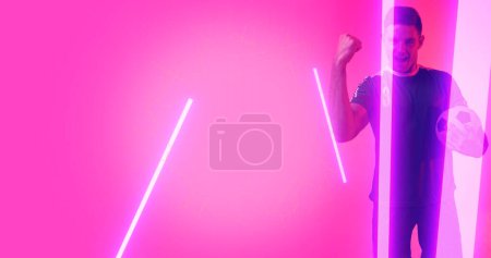 Photo for Composite of caucasian soccer player celebrating success with neon over pink background, copy space. Computer graphic, design, athlete, competitive sport, victory, achievement. - Royalty Free Image