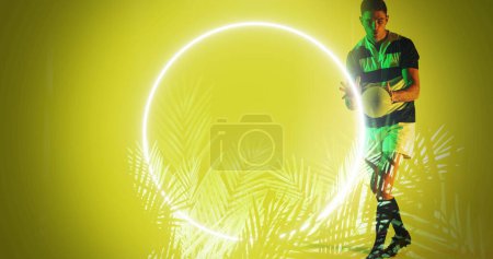 Photo for Caucasian male player catching rugby ball by illuminated circle and plants on yellow background. Copy space, composite, sport, competition, shape, nature, playing, match and abstract concept. - Royalty Free Image