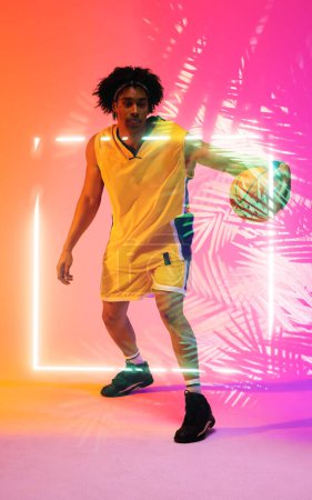 Photo for Full length of biracial player dribbling basketball by illuminated plants and square, copy space. Composite, pink, sport, competition, illustration, glowing, nature and shape concept. - Royalty Free Image