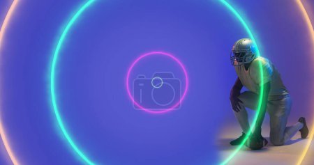 Photo for Composite of illuminated colorful circles and american football player kneeling on blue background. Copy space, neon, sport, competition, illustration, glowing, geometric shape and abstract concept. - Royalty Free Image