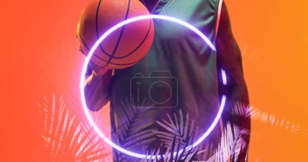 Téléchargez les photos : Milieu du joueur afro-américain de basket-ball avec balle par cercle éclairé et plantes. Espace de copie, composite, main, sport, compétition, illustration, illuminé, nature, forme et abstrait. - en image libre de droit