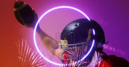 Photo for Close-up of american football player wearing helmet raising hand with ball by circle and plants. Copy space, composite, illuminated, sport, competition, illustration, nature, shape and abstract. - Royalty Free Image