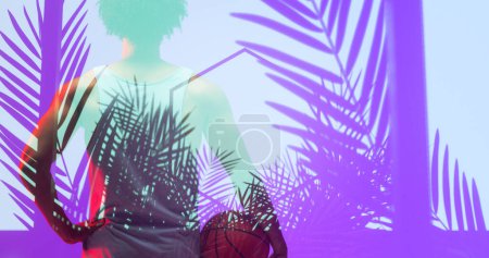 Rear view of biracial basketball player with ball standing over illuminated hexagon and plants. Composite, sport, competition, illustration, glowing, nature, shape and abstract concept. Poster 626919148