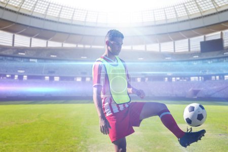 Photo for Biracial young soccer player practicing with ball in stadium, copy space. Sport, competitive sport, skill, athlete, match, bright. - Royalty Free Image