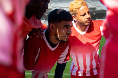 Photo for Multiracial young male soccer players huddling and planning match strategy at stadium on sunny day. Sport, competitive sport, skill, athlete, teamwork, discussion, game plan. - Royalty Free Image