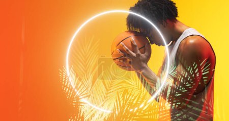 Photo for Side view of biracial basketball player with afro hair holding ball on forehead by circle and plants. Composite, copy space, sport, competition, illustration, illuminated, nature, shape and abstract. - Royalty Free Image