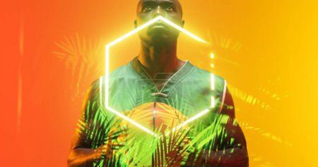 Téléchargez les photos : Composite d'hexagone lumineux et de plantes sur un joueur de basket-ball afro-américain sérieux avec balle. Copier l'espace, sérieux, sport, compétition, illustration, illuminé, nature, forme et abstrait. - en image libre de droit