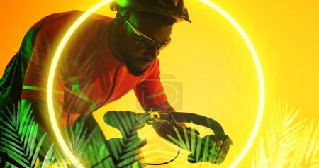 Photo for African american male athlete wearing helmet and eyewear riding bike by circle and plants. Yellow, illuminated, composite, sport, cycling, racing, competition, nature, shape and abstract concept. - Royalty Free Image