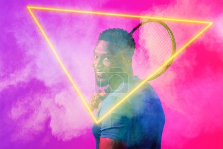 Foto de Jugador afroamericano masculino con raqueta por resplandeciente triángulo en medio del humo sobre fondo de color. Copiar espacio, compuesto, tenis, deporte, competición, forma, juego, partido y concepto abstracto. - Imagen libre de derechos