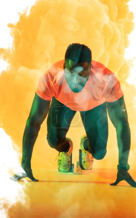 Photo for Confident african american male athlete at starting position against yellow smoky background. Copy space, sprinting, sport, competition, running, racing, portrait and abstract concept. - Royalty Free Image