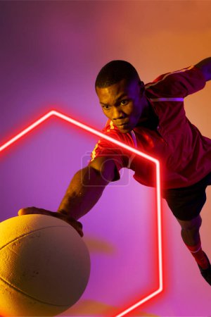 Téléchargez les photos : Joueur afro-américain de rugby masculin attrapant la balle par hexagone illuminé sur fond de dégradé. Espace de copie, composite, sport, compétition, forme, jeu, match et concept abstrait. - en image libre de droit