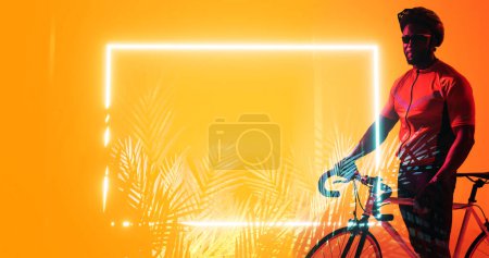 Téléchargez les photos : Athlète afro-américain masculin avec vélo debout par un rectangle éclairé et des plantes, espace de copie. Composite, sport, cyclisme, course, compétition, lunettes, casque, nature, forme et concept abstrait. - en image libre de droit