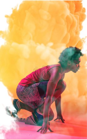 Photo for Side view of african american female athlete crouching at starting position on smoky background. Copy space, sprinting, sport, competition, running, racing and abstract concept. - Royalty Free Image