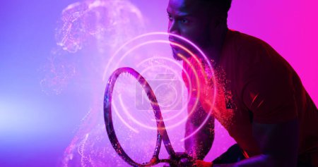 Photo for African american male player holding racket and standing by illuminated circles. Tennis, copy space, composite, sport, competition, playing, match, shape and abstract concept. - Royalty Free Image