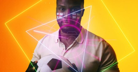 Photo for African american soccer player with england flag's face paint over illuminated geometric shapes. Ball, composite, sport, portrait, competition, copy space, shape, patriotism and abstract concept. - Royalty Free Image