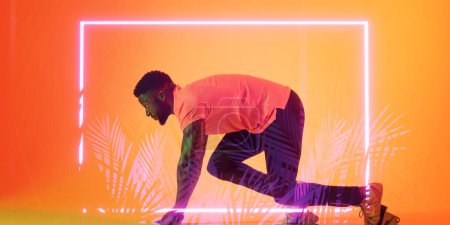 Photo for Side view of african american male athlete at starting position by illuminated rectangle and plants. Copy space, sprinting, sport, competition, running, racing, shape, shape and abstract concept. - Royalty Free Image