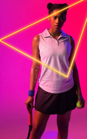 Foto de Jugadora de tenis afroamericana con raqueta y pelota por resplandeciente triángulo sobre fondo rosa. Copiar espacio, compuesto, deporte, competición, forma, contemplación, partido y concepto abstracto. - Imagen libre de derechos