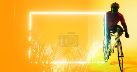 Téléchargez les photos : Pleine longueur d'athlète masculin afro-américain à vélo par des plantes éclairées et rectangle. Espace de copie, jaune, composite, sport, vélo, course, compétition, nature, forme et concept abstrait. - en image libre de droit