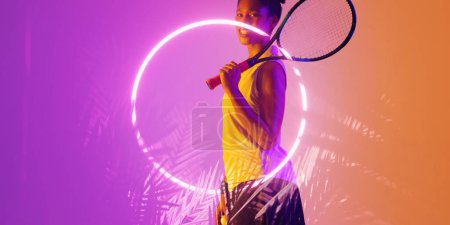 Foto de Jugadora de tenis afroamericana sonriente con raqueta junto a un círculo iluminado y plantas. Copiar espacio, compuesto, deporte, competición, forma, naturaleza, partido y concepto abstracto. - Imagen libre de derechos