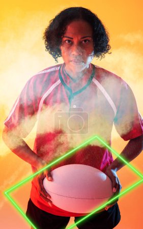 Téléchargez les photos : Joueuse de rugby biraciale confiante avec balle debout au milieu de la fumée par un rectangle éclairé. Espace de copie, composite, sport, compétition, forme, jeu, match et concept abstrait. - en image libre de droit