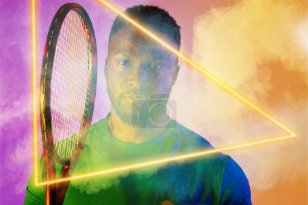 Foto de Retrato de un tenista afroamericano con raqueta por triángulo iluminado en medio del humo. Copiar espacio, compuesto, deporte, humo, forma, competencia, juego, partido y concepto abstracto. - Imagen libre de derechos