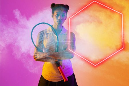 Téléchargez les photos : Femme afro-américaine sérieuse joueuse de tennis avec raquette par hexagone illuminé sur fond fumé. Espace de copie, composite, sport, forme, compétition, jeu, match et concept abstrait. - en image libre de droit
