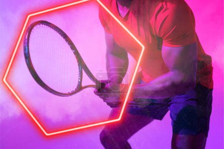Téléchargez les photos : Milieu du joueur de tennis afro-américain tenant la raquette par hexagone illuminé rouge. Espace de copie, composite, sport, compétition, forme, jeu, match, main, fumée et concept abstrait. - en image libre de droit