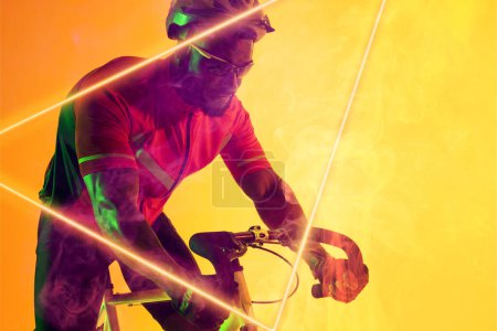 Photo for African american male athlete wearing helmet and eyewear riding bike by illuminated triangle. Copy space, composite, sport, cycling, racing, competition, yellow, shape and abstract concept. - Royalty Free Image
