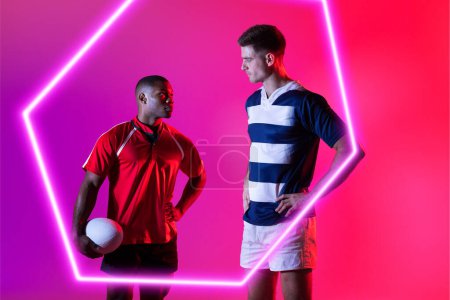 Téléchargez les photos : Des adversaires masculins multiraciaux de rugby se regardent par un hexagone illuminé sur fond rose. Copier l'espace, composite, sport, compétition, regarder, balle, forme, match et concept abstrait. - en image libre de droit