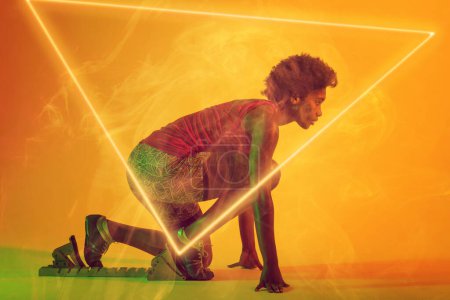 Photo for Side view of african american female athlete at starting position by illuminated triangle. Copy space, sprinting, sport, competition, running, racing, smoke, shape and abstract concept. - Royalty Free Image