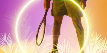 Téléchargez les photos : Midsection of african american male player playing holding tennis racket over circle and plants. Copy space, composite, sport, competition, shape, nature, hand, match and illuminated. - en image libre de droit