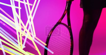 Téléchargez les photos : Midsection of african american male tennis player with racket by glowing lines on pink background. Copy space, composite, sport, competition, neon, leg, illuminated and abstract concept. - en image libre de droit