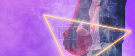Téléchargez les photos : Midsection of african american basketball player with ball and glowing triangle on purple background. Hand, copy space, composite, illuminated, sport, competition, illustration, shape and smoke. - en image libre de droit