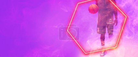 Téléchargez les photos : Section basse du joueur afro-américain de basket-ball avec ballon marchant par hexagone sur fond violet. Espace de copie, composite, illuminé, sport, compétition, illustration, concept de forme et de fumée. - en image libre de droit
