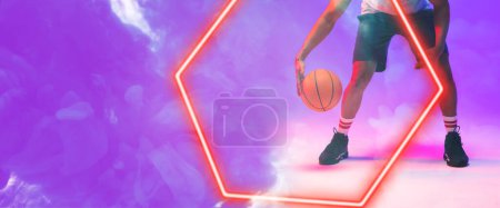 Téléchargez les photos : Low section of biracial basketball player dribbling ball by hexagon over smoky background. Copy space, composite, hand, leg, illuminated, sport, competition, illustration, shape and abstract concept. - en image libre de droit