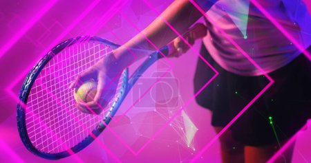 Téléchargez les photos : Midsection of biracial female tennis player playing with racket and ball over pink geometric shapes. Illuminated, copy space, composite, sport, competition, neon, hand and abstract concept. - en image libre de droit
