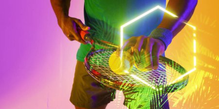 Téléchargez les photos : Midsection of african american male player with tennis racket and balls over plants and rectangle. Copy space, composite, sport, competition, shape, playing, nature, hand, match and illuminated. - en image libre de droit