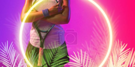 Téléchargez les photos : Illuminated circle and plants over midsection of african american female player holding racket. Copy space, composite, tennis, sport, competition, shape, nature, playing, match, hand, abstract. - en image libre de droit