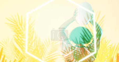 Photo for Rear view of biracial female rugby player throwing ball over illuminated hexagon and plants. Copy space, composite, sport, competition, shape, nature, playing, match and abstract concept. - Royalty Free Image