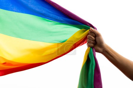 Foto de Hand holding rainbow coloured flag with copy space on white background. Pride month, equality, lgbt and human rights concept. - Imagen libre de derechos