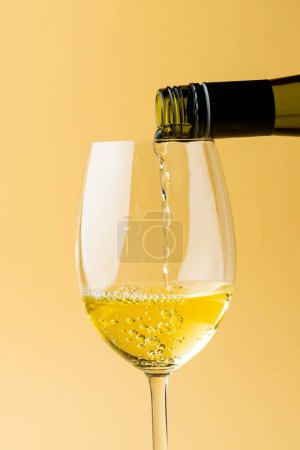 Téléchargez les photos : Bouteille de vin blanc et verre sur fond jaune, avec espace de copie. Semaine du vin, concept boisson et célébration. - en image libre de droit