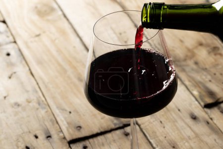 Téléchargez les photos : Bottle of red wine and glass on wooden background, with copy space. Wine week, drink and celebration concept. - en image libre de droit