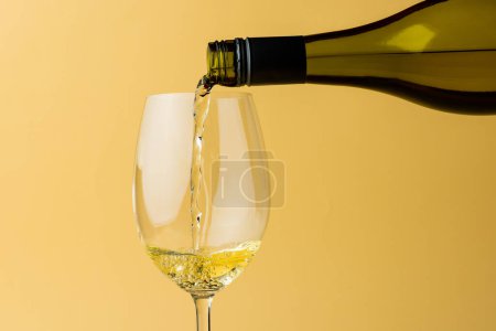Téléchargez les photos : Bottle of white wine and glass on yellow background, with copy space. Wine week, drink and celebration concept. - en image libre de droit