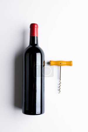 Téléchargez les photos : Bottle of red wine and corkscrew on white background, with copy space. Wine week, drink and celebration concept. - en image libre de droit