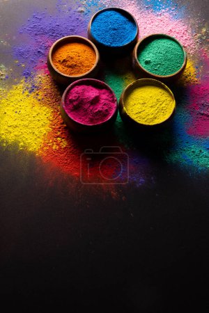 Téléchargez les photos : Close up of multi coloured powder in bowls and copy space on black background. Holi festival, colour, hindu tradition and celebration concept. - en image libre de droit