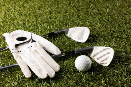 Foto de Close up of white glove, golf ball and golf clubs on grass with copy space. Golf, sports and competition concept. - Imagen libre de derechos