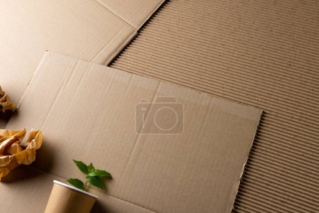 Photo for Close up of pieces of paper and cup with plant on cardboard background with copy space. Global ecology and recycling concept. - Royalty Free Image