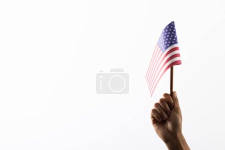 Foto de Mano sosteniendo bandera polo de EE.UU. sobre fondo blanco con espacio de copia. Día conmemorativo, patriotismo y concepto de celebración. - Imagen libre de derechos