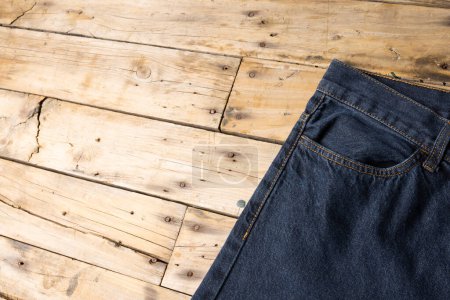 Foto de Pantalón vaquero azul oscuro sobre superficie de madera. Ropa, moda, diseño, tejidos, materiales y concepto de compras. - Imagen libre de derechos